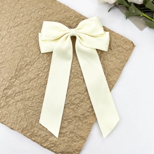 Détail d'un nœud papillon en satin crème avec de longs rubans sur un fond de papier texturé