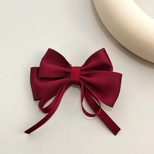 Close-up of elegant burgundy silk ribbon bow hair clip with layered satin streamers