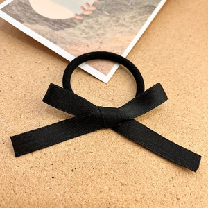 Dettaglio ravvicinato di un elastico per capelli con fiocco nero in raso su sughero