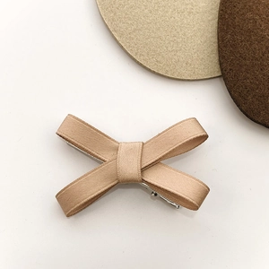 Detailed top view of a champagne ribbon bow hair clip with textured grosgrain fabric