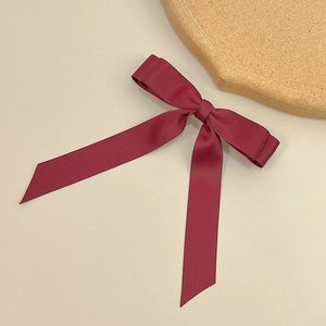 Macro detail of wine red satin double bow hair clip with long elegant ribbons
