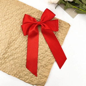 Élégante grande pince à cheveux en satin rouge avec de longs rubans sur papier texturé
