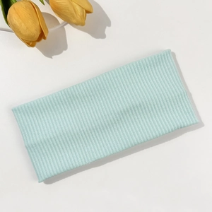 Close-up of light blue ribbed knit headband texture on a minimalist white background
