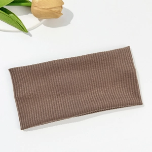 Detailed view of coffee brown knitted headband with elastic vertical ribbed texture