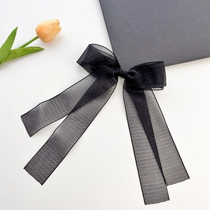 Elegant black organza bow hair clip with long ribbons on a white background with a tulip