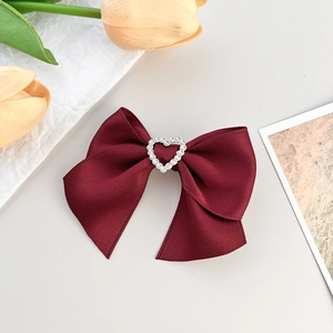 Barrette à cheveux nœud rouge vin vintage avec cœur en strass sur fond gris épuré
