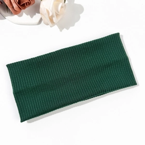 Detailed texture of dark green ribbed knit headband on white background with floral accents