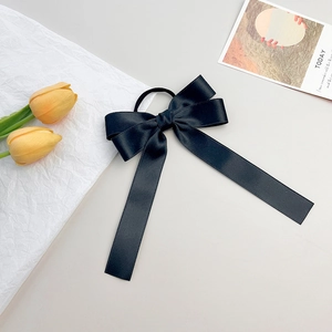 Détail d'un chouchou en satin noir avec de longs rubans et des tulipes jaunes