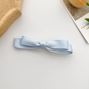 Fermaglio per capelli a doppio fiocco azzurro stile francese su uno sfondo minimal