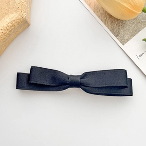 Dettaglio del fermaglio per capelli con fiocco in nastro nero e tessuto grosgrain a strati