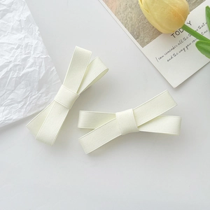 Détail de deux barrettes à cheveux en forme de nœud crème en tissu côtelé