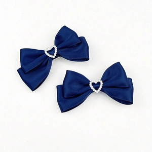 Détail des barrettes nœuds bleu marine avec centres en cœur sertis de strass brillants
