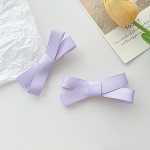 Gros plan de deux barrettes à nœuds violet lavande avec texture ruban côtelé sur fond blanc
