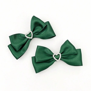 Détail de barrettes nœuds vert foncé avec boucles en forme de cœur serties de cristaux