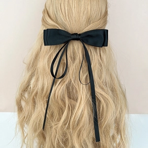 Pince à cheveux élégante en satin noir avec longs rubans sur cheveux blonds