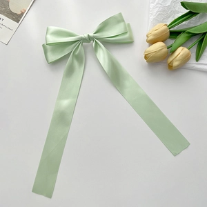 Detailed macro view of mint green satin bow hair clip with elegant long ribbons