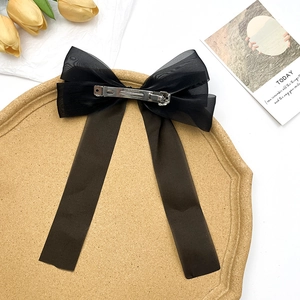 Barrette nœud élégante en tulle noir avec de longs rubans sur un plateau