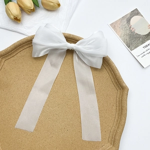 Détail d'une pince à cheveux nœud en organza blanc sur un plateau avec tulipe