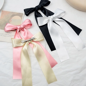 Detailed view of satin bow hair clips in black, white, pink, and champagne with metal clips