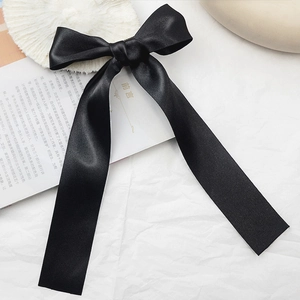 Elegant large black satin ribbon bow hair clip with long streamers on white background