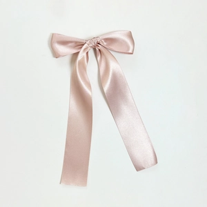 Close-up of elegant champagne pink satin bow hair clip with long silk streamers