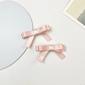 Vue détaillée de barrettes nœuds en satin rose montrant la texture soyeuse et le design