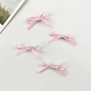 Vue détaillée de quatre barrettes à nœuds en ruban satin rose avec clips en métal