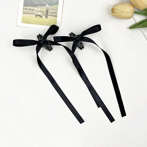 Coppia di eleganti fermagli per capelli in raso nero con nastri lunghi su sfondo bianco