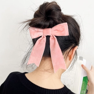 Detailed view of a pink velvet bow hair clip with ribbons on an elegant bun hairstyle