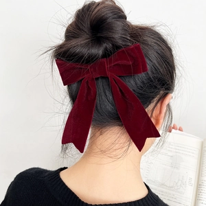 Macro view of large burgundy velvet bow hair clip with ribbons on dark hair