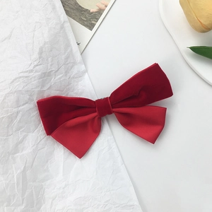 Detailed view of red velvet and satin bow hair clip on a minimalist white background