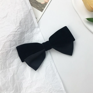 Detailed texture of black velvet and twill satin bow hair clip on minimalist background