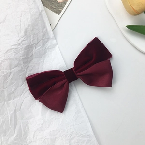 Macro detail of wine red velvet and ribbed ribbon bow hair clip with vintage texture
