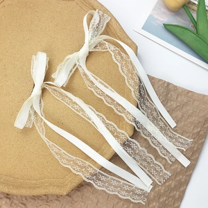Close-up of beige silk satin ribbon hair clips with lace details on a wooden tray