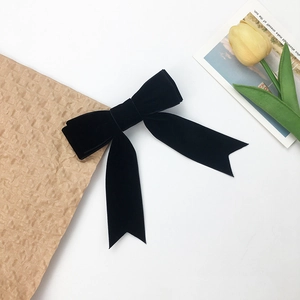 Elegant black velvet bow hair clip with long ribbons on a white artistic background