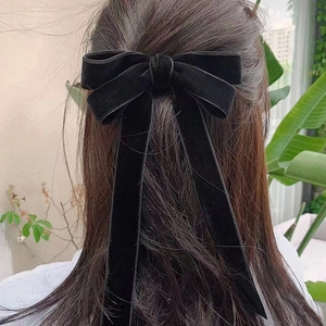 Elegant large black velvet bow hair clip with long streamers on female model in nature
