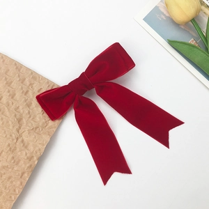 Detailed view of red velvet bow hair clip with long ribbons on a white background