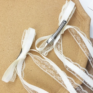 Detail of white lace bow hair clips with long ribbons and silver alligator metal clips