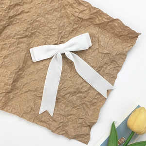 Elegant white velvet double bow hair clip with long ribbons on a decorative background
