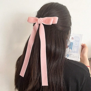 Detail of pink velvet bow hair clip with long ribbons worn on a half-up hairstyle