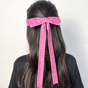 Pink velvet hair clip with long ribbons worn on dark hair back view close-up detail