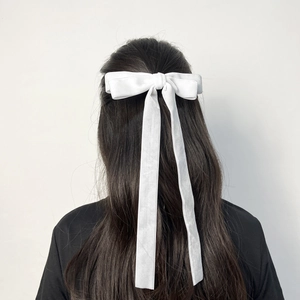 Detail of white velvet bow hair clip with long ribbons on brunette hair