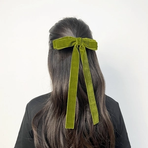 Detail of velvet bow hair clip with long ribbons worn on model's long hair