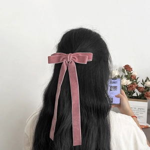 Close-up of elegant lotus pink velvet bow hair clip with long streamers on a hairstyle