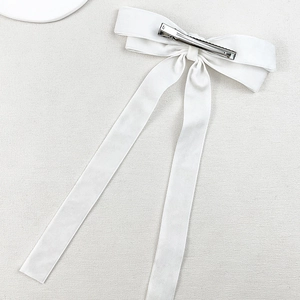 Detail view of white velvet bow hair clip showing silver metal duckbill fastener