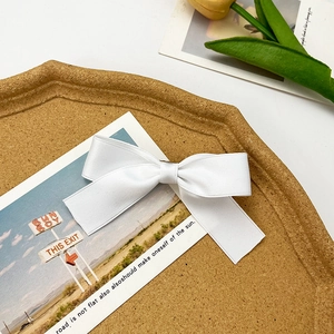 Elegant white satin ribbon bow hair clip on a cork tray with tulip decoration