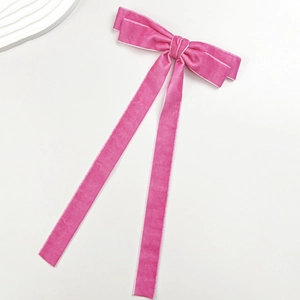 Detailed view of pink velvet ribbon bow hair clip with elegant long streamers on white base
