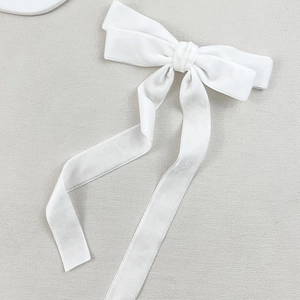 Detailed macro view of high-quality white velvet ribbon bow hair clip with long streamers