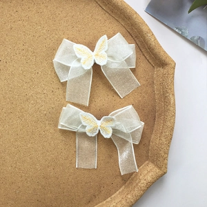 Dettaglio di fermagli per capelli in pizzo organza bianco con farfalle ricamate