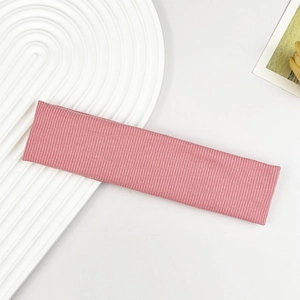 Detailaufnahme eines rosa gerippten Yoga-Stirnbands auf einem weißen Tablett